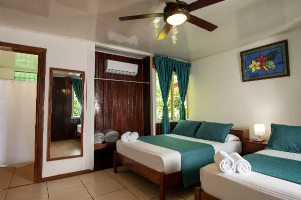 Habitación estándar en Valverde Glamping & Ecolodge con vistas al jardín, dos camas dobles y decoración tropical.